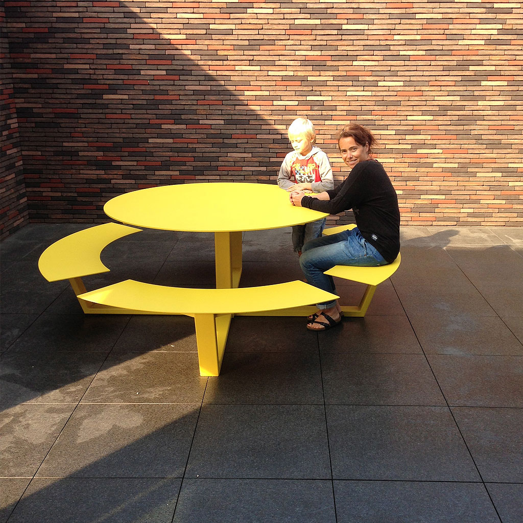 Father & Son Sat At Yellow La Grand Ronde CIRCULAR PICNIC TABLE Is A Round STEEL Picnic Table In HIGH QUALITY Picnic Set Materials By Cassecroute DESIGNER Picnic FURNITURE. Grande Ronde Modern Round Picnic Table And Benches Seats 8-12, And Is Available In Any RAL Colour Of Your Choice.