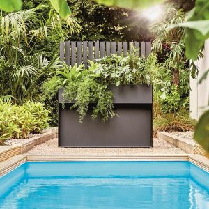 Poolside shot of Ticino raised plant pot and trellis in Anthracite HPL surrounded by lush tropical planting